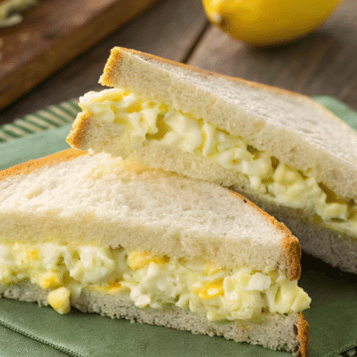 Masters Egg Salad Recipe sandwich served on white bread with lemon wedge