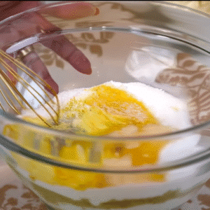 Whisking mascarpone, sugar, egg yolks, and crushed pistachios in a bowl for homemade Pistachio Tiramisu